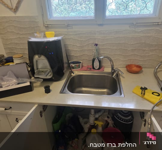 כיור מטבח עם ברזים וכלים שונים על השיש